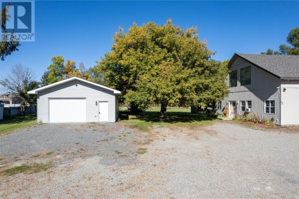 Exterior view of a grey detached garage and a two-story grey building with a large tree nearby. - 36 Mcintyre Street, Nairn Centre