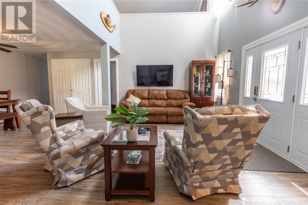 Living room with light grey walls, patterned armchairs, a leather sofa, and a television. - 36 Mcintyre Street, Nairn Centre