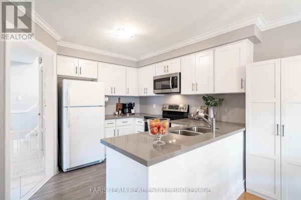 U-shaped kitchen with white cabinets, grey countertops, stainless steel appliances, and a double sink. - 36 Red Oak Drive, Barrie