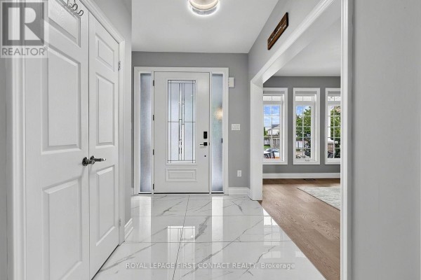 Interior entryway with white tiled floor, white double doors, and a view into the living room. - 36 Regalia Way, Barrie