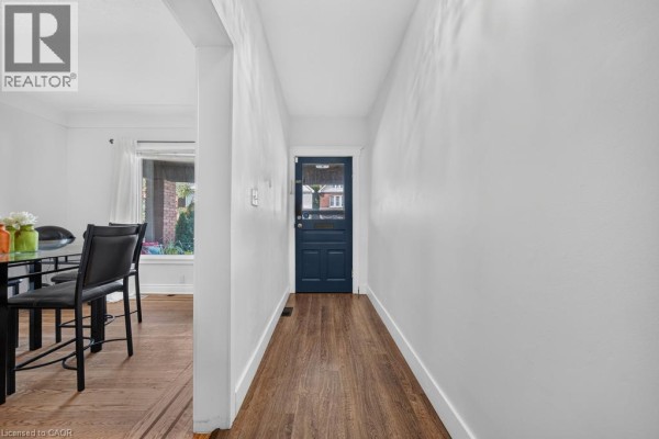 Interior hallway with white walls, wood-look flooring, and a dark blue door. - 36 Sherman Avenue N, Hamilton