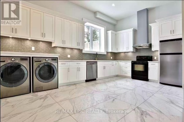 White kitchen cabinets with grey backsplash, stainless steel appliances, washing machine, and dryer. - 36 Sussex Avenue, Richmond Hill