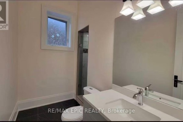 Bathroom with a white vanity, toilet, glass shower stall, and decorative window. - 36 Sussex Avenue, Richmond Hill