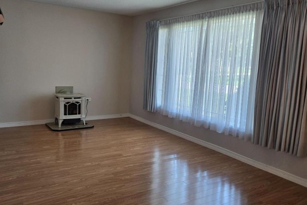 Living room with wood laminate flooring, white electric fireplace, and light grey curtains. - 36 Weeping Willow Drive, Innisfil