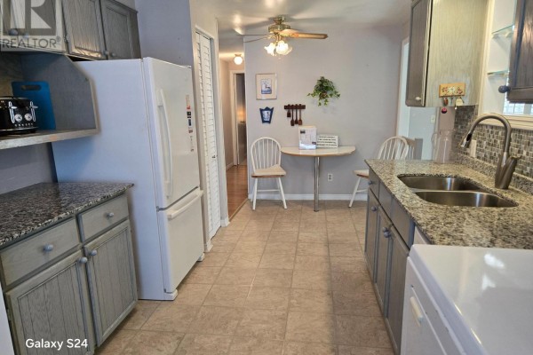 Kitchen with grey cabinets, granite countertops, a double sink, and a refrigerator. - 36 Weeping Willow Drive, Innisfil