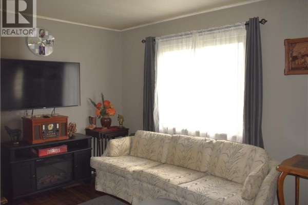 Bedroom with a bed, a dresser, double closet doors, and an open doorway revealing a hallway. - 36 Woodhouse Avenue, Port Dover
