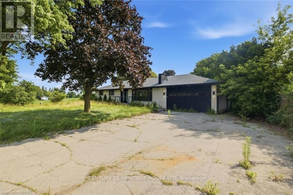 View of the house from the driveway, showing the garage and surrounding trees. - 360 Bishopsgate Road, Brant