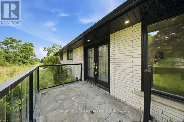 Close-up of the stone patio with glass railings and double doors on the side of the house. - 360 Bishopsgate Road, Brant
