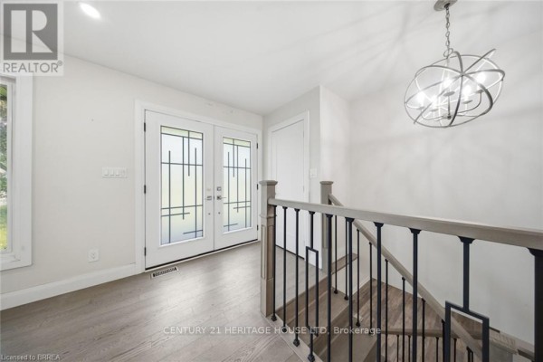 Interior view of the foyer with double glass doors and a staircase with black railings. - 360 Bishopsgate Road, Brant