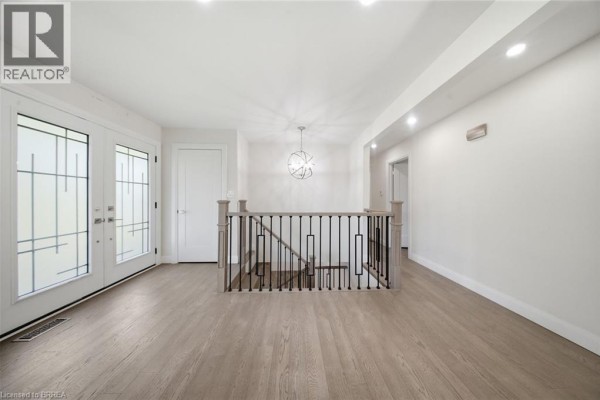 Spacious interior entryway with light wood floors, double doors, and a view of the staircase. - 360 Bishopsgate Road, Burford