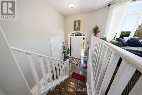 Interior view of a bright foyer with a staircase, white railing, and a view of the front door. - 360 Dover Avenue, Norfolk