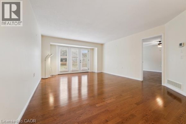 Living room with hardwood floors, white walls, and double glass doors. - 360 Erbsville Road Unit# 18, Waterloo