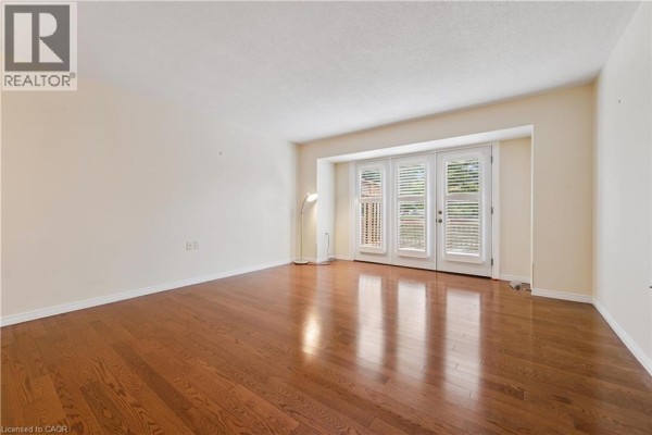 Living room with hardwood floors, light cream walls, and double glass doors. - 360 Erbsville Road Unit# 18, Waterloo
