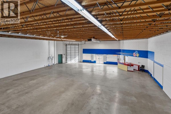 Large open space with concrete flooring and a service counter area. - 360 Spedding Court Unit# 4, Kelowna