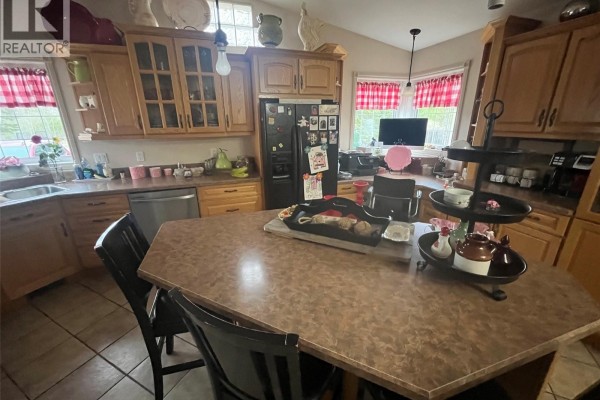 Kitchen with oak cabinets, granite countertops, an island, and dining chairs. - 3600 55 Highway, Prince Albert