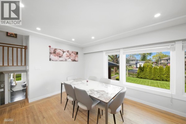 Dining area with a white table, grey chairs, and a large window overlooking the backyard. - 3600 Raymond Avenue, Richmond