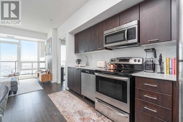 Modern kitchen with dark wood cabinets, stainless steel appliances, white countertop, and backsplash. - 3602 - 2212 Lake Shore Boulevard, Toronto