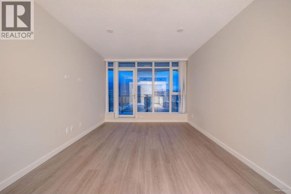 Empty living room with light wood floors and floor-to-ceiling windows with city views. - 3602 1182 Westwood Street, Coquitlam