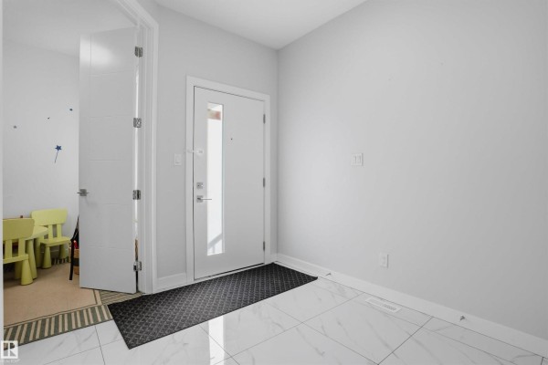 Interior entryway with a white front door with glass, gray walls, and white tile flooring. - 3602 41 Ave, Beaumont