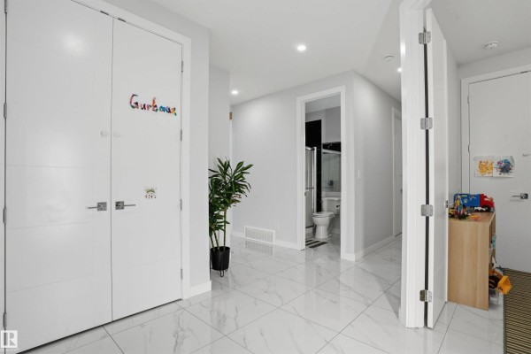 Hallway with white doors, gray walls, white tile flooring, a potted plant, and a view into a bathroom. - 3602 41 Ave, Beaumont
