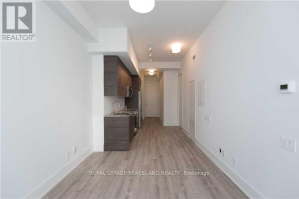 Interior view of a small apartment showing a kitchenette and living area with white walls. - 3604 - 28 Wellesley Street E, Toronto