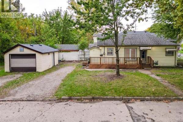 Corner view of a beige bungalow with a lawn and a detached garage. - 3605 Bloomfield, Windsor