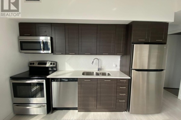 Modern kitchen with dark wood cabinets, stainless steel appliances, and white countertops. - 3606 - 2212 Lakeshore Road W, Toronto