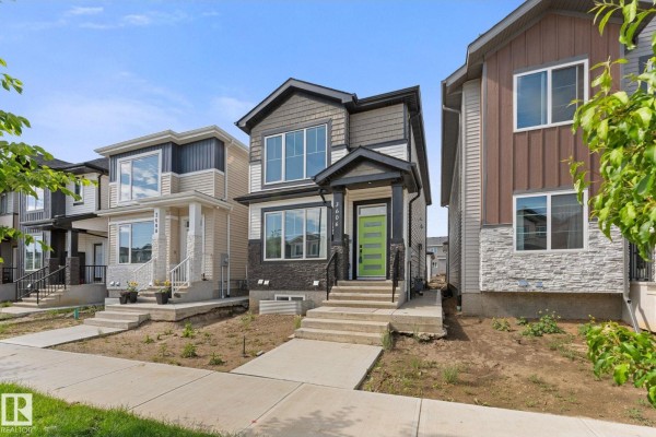 Exterior view of a beige apartment building with balconies and mature trees. - 3606 42 Av, Beaumont