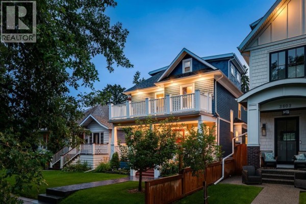 Front exterior view of a blue two-story house with a porch and grass yard. - 3607 7 Street Sw, Calgary