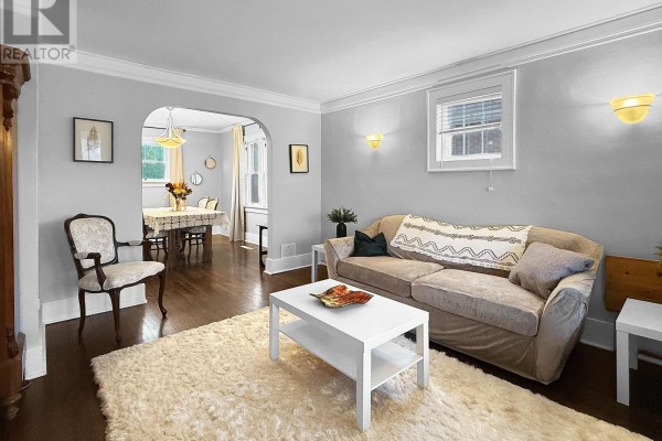 Living room with a beige sofa, arched doorway to dining room, and hardwood floors. - 361 Bowen Road, Fort Erie