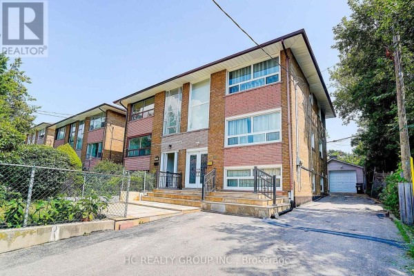 Exterior view of the duplex and driveway with a detached garage. - 361 Highfield Road, Toronto