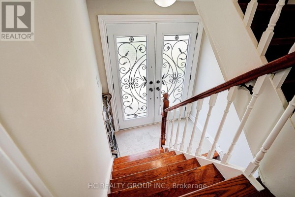 Interior view looking down wooden stairs towards a double glass door. - 361 Highfield Road, Toronto