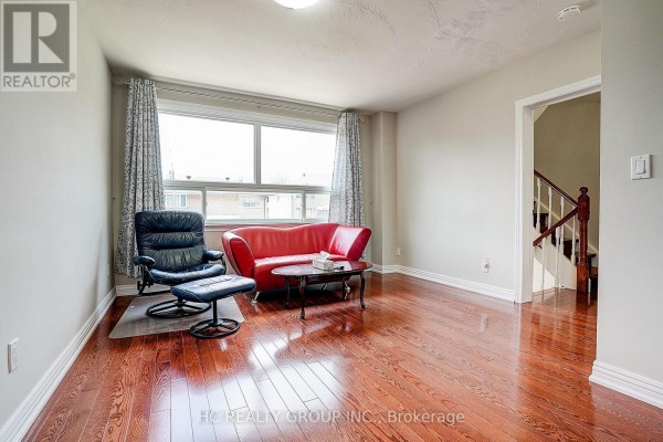 Living room with a large window, red sofa, recliner, and view of stairs. - 361 Highfield Road, Toronto