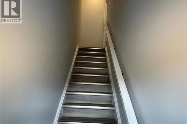 Interior staircase with grey wood-look laminate treads and white risers and railings. - 361 Quarter Town Line Unit# 108, Tillsonburg