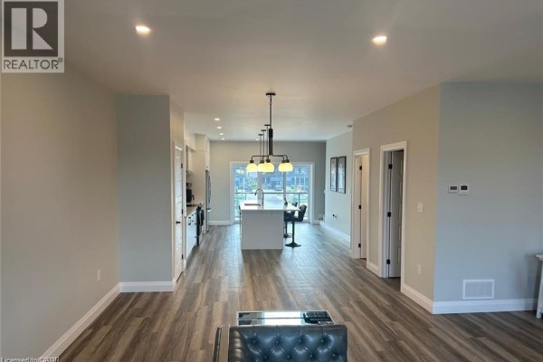 View from dining area into open concept living space, showing kitchen island and living room. - 361 Quarter Town Line Unit# 108, Tillsonburg