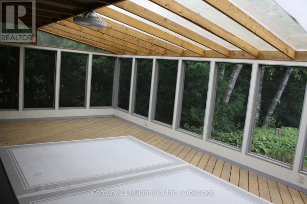 Interior of a sunroom with wood floors, a peaked ceiling, and floor-to-ceiling windows. - 361 Tyendinaga Drive N, Saugeen Shores