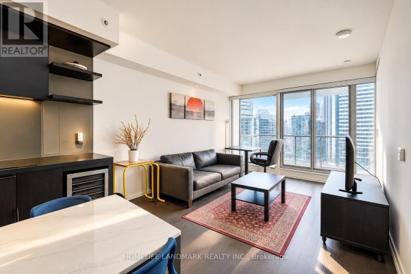 Living room with a grey sofa, coffee table, media console, and large windows with city views. - 3610 - 70 Temperance Street, Toronto