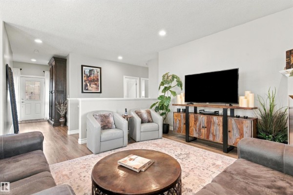 Living room with a television, two chairs, and a view toward the entrance. - 3611 61 St, Beaumont