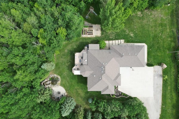 Overhead view of the property showcasing the house, deck, water feature, garden beds, and surrounding woodland. - 36131 Pr 303 Road, Steinbach