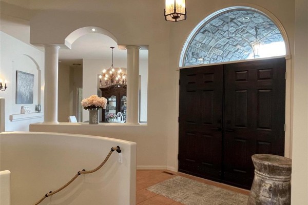 Interior view of the entryway looking towards the dark wood double doors and an arched stone ceiling detail. - 36131 Pr 303 Road, Steinbach