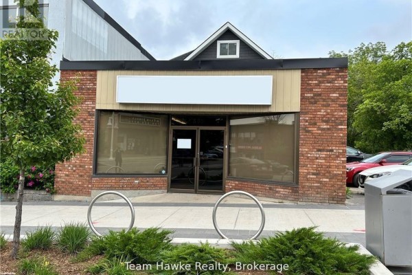 Storefront with brick and tan siding, glass double doors, and a blank white sign above. - 361&365 King Street, Midland