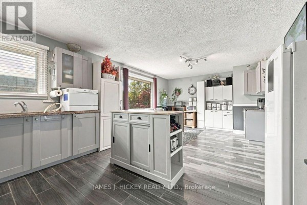 A bright kitchen with light grey cabinets, a central island, and a large window with a view of trees. - 36148 Highway 17 Highway, Laurentian Hills