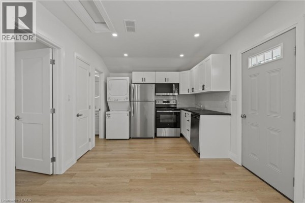 Kitchenette area with white cabinetry, stainless steel appliances, and a stackable washer and dryer. - 362 Gatfield Avenue Unit# 2, Welland