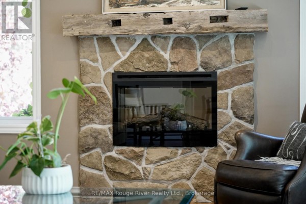 Stone fireplace with reclaimed wood mantel and gas insert, next to leather armchair - 3625 Alnwick Hill Road Hamilton Township