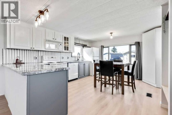 Kitchen counter space with grey cabinets, white cabinets, a white stove, and a sink. - 364, 6220 17 Avenue Se, Calgary