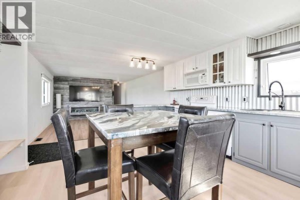 Open concept kitchen and dining area with white cabinets, a grey island, and a dining table. - 364, 6220 17 Avenue Se, Calgary