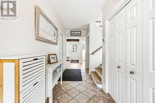 Hallway with tiled floor, stairs to the right, and multiple closed doors. - 364 Fennell Avenue W, Hamilton