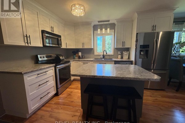 Modern kitchen with white cabinets, granite countertops, and stainless steel appliances. - 364 Genier Road, Cochrane