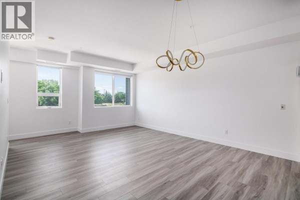 Empty open concept living and dining area with wood flooring and large windows. - 3642 Mission Springs Drive Unit# 103, Kelowna