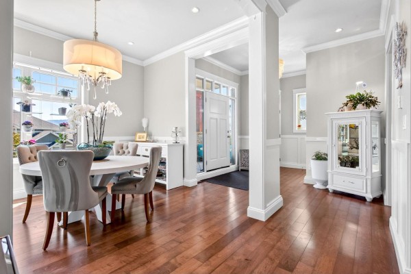 Covered front porch with two teal chairs, a small table, and a grey front door. - 36497 Carnarvon Court, Abbotsford